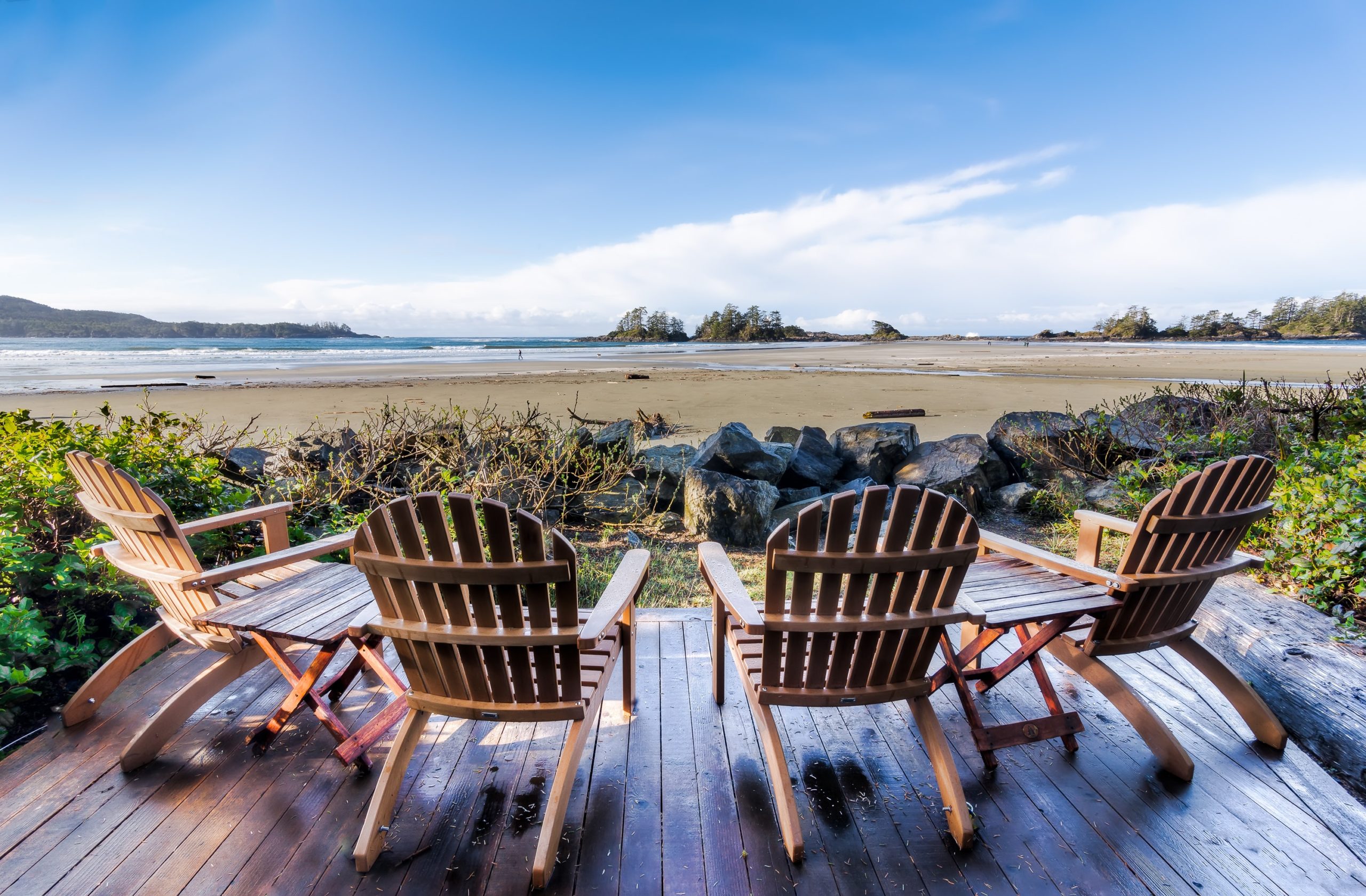Four brown adirondack chairs facing beach